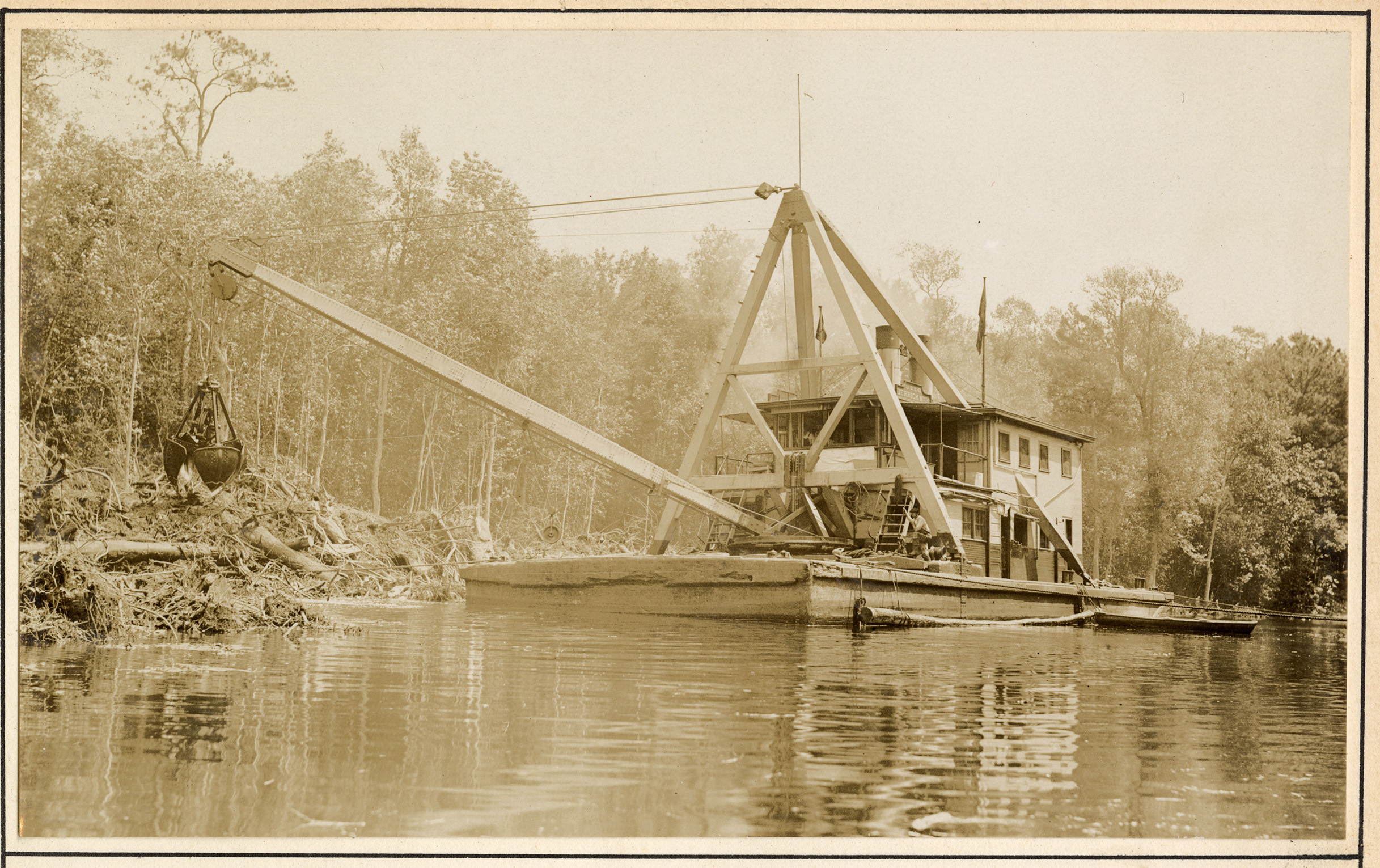 Small dredge in water surrounded by trees